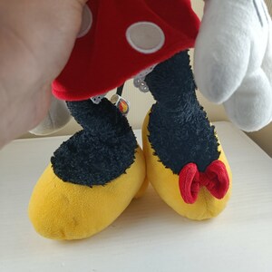 May include: A red and white polka dot dress with a white lace trim and yellow shoes with a red bow. The shoes are on a white surface.