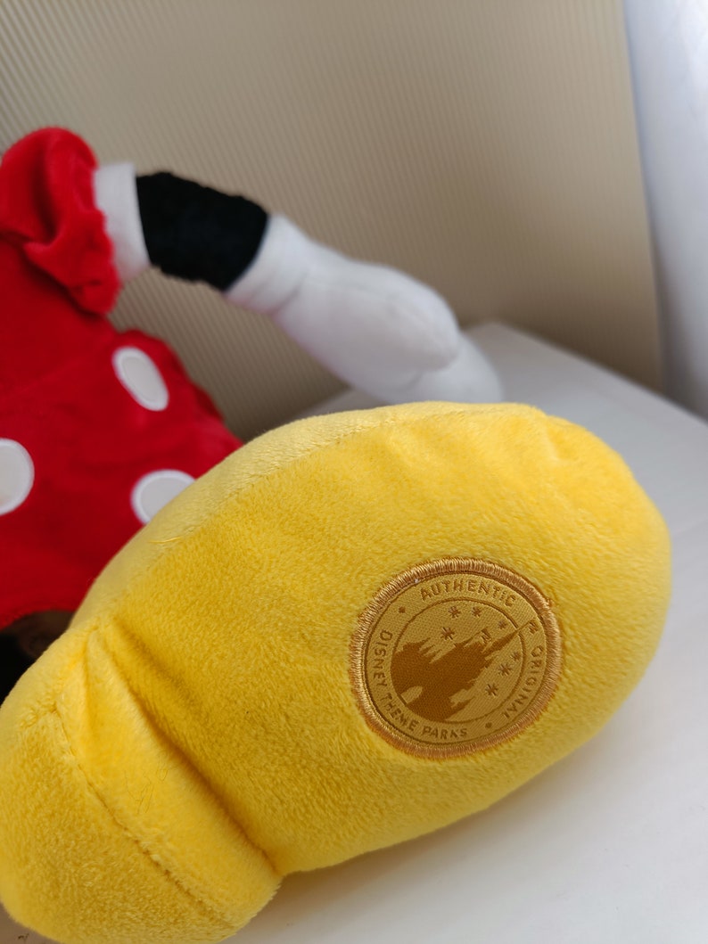 May include: Yellow plush Mickey Mouse glove with a gold Disney Theme Parks Authentic Original tag.