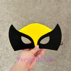 May include: A black and yellow felt mask with eye holes. The mask has a pointed shape at the top and two pointed shapes on the sides.