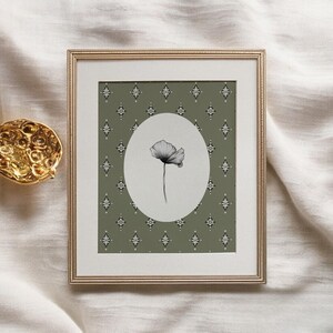 May include: A framed print with a green background featuring a white flower with a black outline in a white oval. The background has a repeating pattern of small white diamonds.