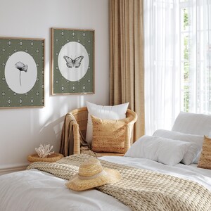May include: A white bed with a beige knitted throw blanket and a straw hat. The bed has white linens and pillows. There are two framed prints on the wall behind the bed, one with a butterfly and the other with a flower.
