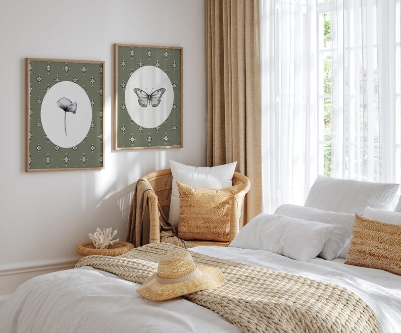 May include: A white bed with a beige knitted throw blanket and a straw hat. The bed has white linens and pillows. There are two framed prints on the wall behind the bed, one with a butterfly and the other with a flower.