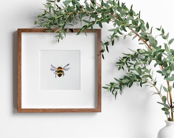 May include: A framed watercolor painting of a bumblebee with brown and yellow stripes and clear wings. The frame is made of dark wood and has a white mat.