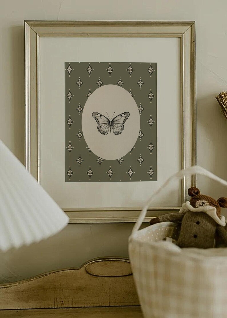 May include: A framed print with a green background and a white oval containing a black and white butterfly illustration. The background has a repeating diamond pattern.