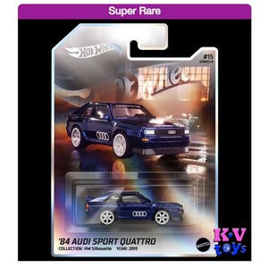 Puede incluir: Un coche azul Hot Wheels Audi Sport Quattro de 1984, parte de la serie HW Silhouette, en una vitrina con fondo blanco. El coche tiene ruedas negras y un interior negro. El coche está etiquetado con "#15" y "Serie 8".