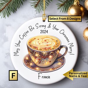 May include: White ceramic Christmas ornament with a colorful illustration of a coffee cup with a festive design. The ornament has the text "May Your Coffee Be Strong & Your Christmas Merry!" and the year "2024". The name "Francis" is printed at the bottom of the ornament.