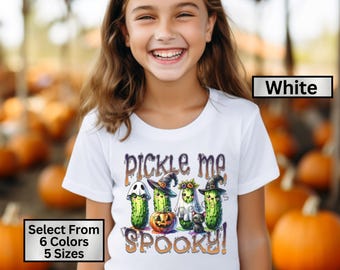 May include: White t-shirt with a graphic of four pickle characters dressed in Halloween costumes. The text "pickle me spooky!" is printed on the shirt.