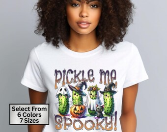 May include: White t-shirt with a graphic of four pickle characters dressed as ghosts and witches. The text "Pickle Me Spooky!" is printed on the shirt.