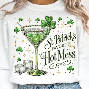 May include: White sweatshirt featuring a green cocktail with shamrocks and the text "St Patrick's Favorite Hot Mess." The design includes ice cubes, stars, and a green drink in a martini glass.