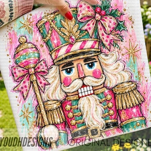 May include: A square canvas print featuring a colorful illustration of a nutcracker soldier wearing a teal and pink uniform with gold accents, holding a matching scepter, adorned with a large pink polka dot bow and holly leaves.