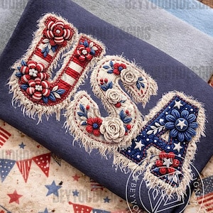 May include: A navy blue textile with the letters "USA" embroidered in red, white, and blue. The letters are decorated with floral and star motifs, and have a fringed border. The design evokes a patriotic theme.