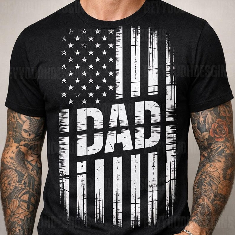 Puede incluir: Camiseta negra con un dise&ntilde;o de bandera estadounidense desgastada y la palabra "DAD" en blanco. El dise&ntilde;o de la bandera incluye estrellas blancas y rayas verticales. Una prenda patri&oacute;tica.
