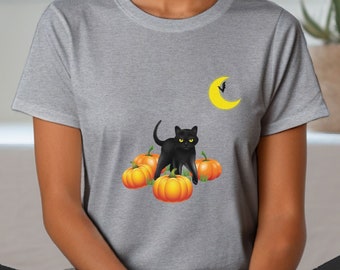 Może przedstawiać: Szara koszulka z motywem Halloween. Grafika przedstawia czarnego kota z żółtymi oczami na pomarańczowych dyniach, żółty półksiężyc i nietoperza. Koszulka ma okrągły dekolt.