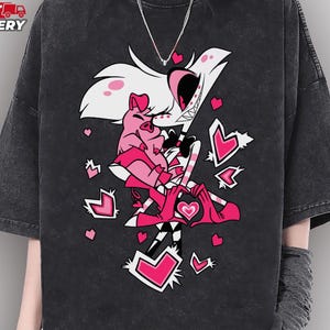 May include: Black t-shirt with a graphic of a cartoon character with white hair, pink accents, and hearts. The shirt has short sleeves and a relaxed fit. The text "COLOR: PEPPER COMFORT COLORS" and "FAST DELIVERY" are visible.