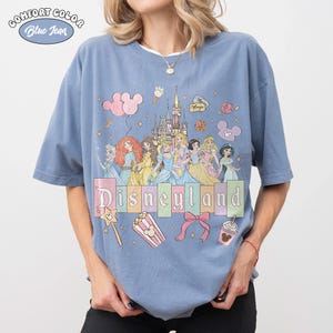 May include: A white ceramic mug with a black handle and the text "But First, Coffee" in a black, handwritten-style font. The mug is on a white surface.