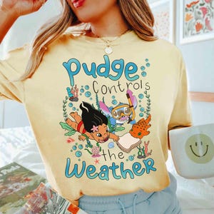 May include: A white ceramic mug with a black handle and the text "But First, Coffee" in a handwritten style. The mug is on a white surface. The mug is approximately 10 cm tall.