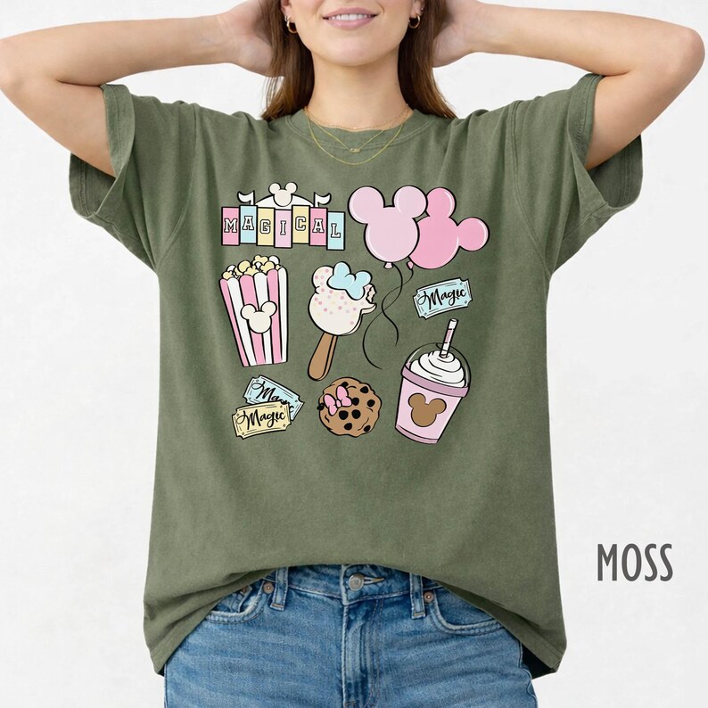 May include: Moss green t-shirt with colorful graphic illustrations of popcorn, ice cream, a cookie, a drink, and balloons. The word "MAGICAL" is printed at the top. The word "Magic" is printed on tags.