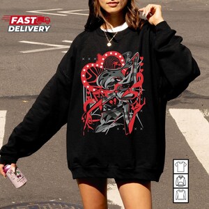 Puede incluir: Sudadera negra con un dise&ntilde;o gr&aacute;fico en rojo, gris y blanco. El dise&ntilde;o presenta un personaje estilizado con un elemento en forma de coraz&oacute;n y formas geom&eacute;tricas. El texto "FAST DELIVERY" es visible.