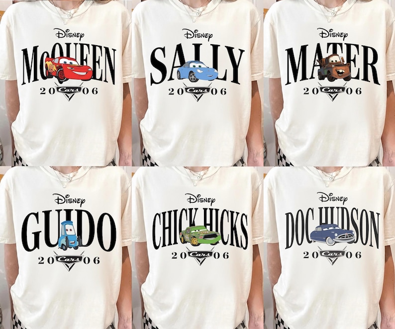 Op de afbeelding: Cr&egrave;mekleurige t-shirts met Disney Cars-personages. Elk shirt toont de naam van een ander personage in grote zwarte letters, samen met een bijbehorende autografiek en de tekst "20 Cars 06".