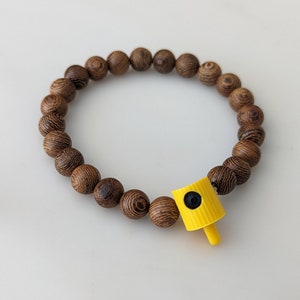 May include: A wooden bead bracelet with a yellow spray paint cap charm.