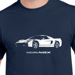 May include: A navy blue t-shirt with a white silhouette of an Acura NSX sports car. The car is centered on the shirt and the text "ACURA NSX" is printed below the car.