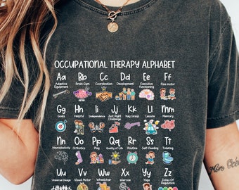 May include: Dark grey t-shirt with the "Occupational Therapy Alphabet" printed on it. The design is an alphabet chart with colourful illustrations representing occupational therapy concepts. Terms include "Adaptive Equipment," "Brain Gym," and "Fine Motor."