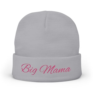 May include: A light gray beanie with the embroidered text "Big Mama" in pink script. The beanie is a knit style with a folded cuff. The hat is a casual accessory.