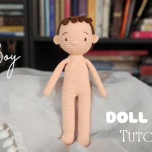 Puede incluir: Una base de muñeca de ganchillo con forma de niño, con piel melocotón claro y cabello castaño. La muñeca tiene un diseño sencillo, con los brazos y las piernas extendidos. El texto en la imagen dice "Boy" y "DOLL BASE TUTORIAL".