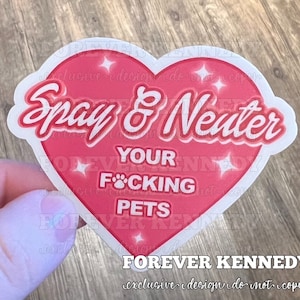 May include: Pink heart-shaped sticker with the text "Spay & Neuter Your F*cking Pets" in white lettering. The sticker has a white border and sparkles around the edges. The text "FOREVER KENNEDY exclusive design do not copy" is printed below the heart.
