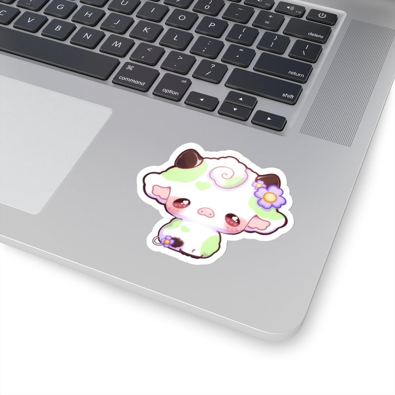 Puede incluir: Una ilustraci&oacute;n de dibujos animados de una vaca blanca con manchas verdes y una flor morada en la cabeza. La vaca tiene ojos grandes y redondos y una nariz rosa.