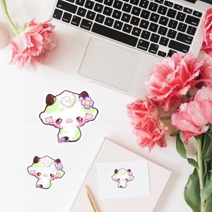 Puede incluir: Tres adorables pegatinas de vaca de dibujos animados con manchas verdes y blancas, mejillas rosadas y flores moradas. Las pegatinas est&aacute;n sobre un fondo blanco.
