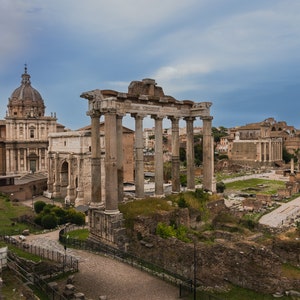 Puede incluir: Una vista panorámica del Foro Romano en Roma, Italia. Las ruinas de antiguos edificios romanos son visibles, incluyendo el Templo de Saturno, el Arco de Septimio Severo y la Basílica Julia. El Foro es un destino turístico popular y un sitio declarado Patrimonio de la Humanidad por la UNESCO.