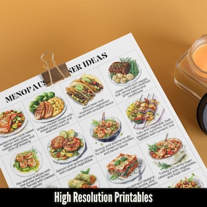 May include: A printed sheet featuring illustrated dinner ideas, such as tacos, salmon, and lasagna, held by a gold binder clip. The text at the bottom reads "High Resolution Printables". The word "MENOPAUSE" is at the top.