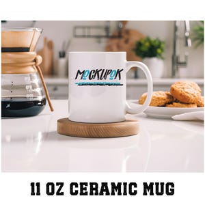 Puede incluir: Taza de cerámica blanca con un diseño "MOCKUP" en negro y azul y una línea negra debajo. La taza está sobre un posavasos de madera en una superficie blanca.