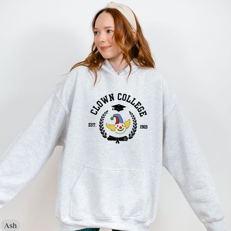 May include: A gray hooded sweatshirt with the text "Clown College" in black lettering, a clown with a graduation cap, and the text "Est. 1969".