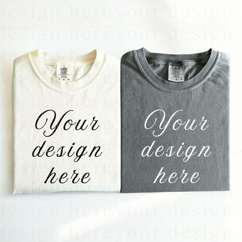 May include: Two folded t-shirts, one white and one grey, with the text "Your design here" printed on each.