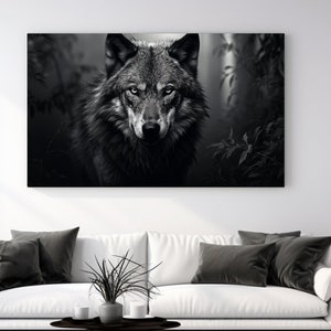 Pode incluir: Uma fotografia a preto e branco de um lobo a olhar diretamente para a câmara. O lobo está num cenário de floresta escura.