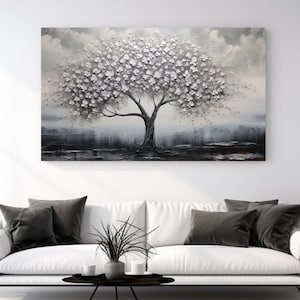May include: A black and white painting of a tree with white blossoms. The tree is set against a gray background with a hint of blue. The painting is framed and hanging on a white wall.