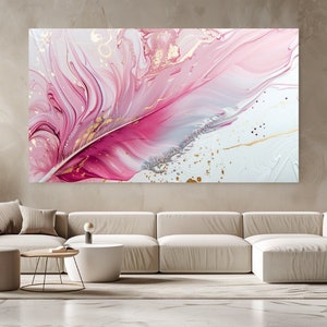 Puede incluir: Impresión de arte abstracto con una pluma rosa y blanca con detalles dorados y plateados. La impresión se muestra en una pared sobre un sofá blanco en una sala de estar moderna.