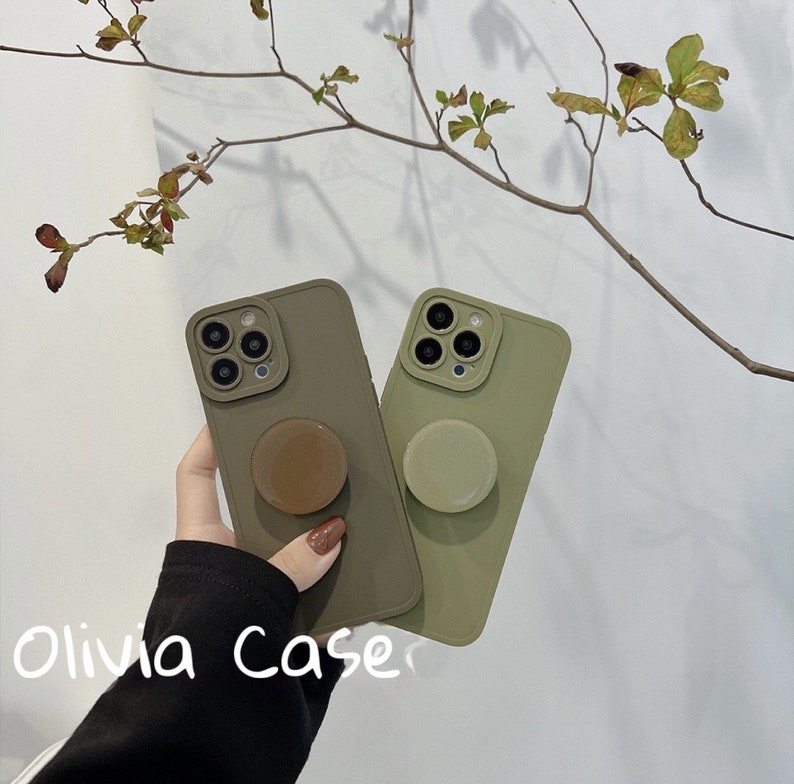 May include: Two olive green phone cases with a pop socket on each. The pop sockets are brown and green. The text "Olivia Case" is visible in the bottom left corner of the image.