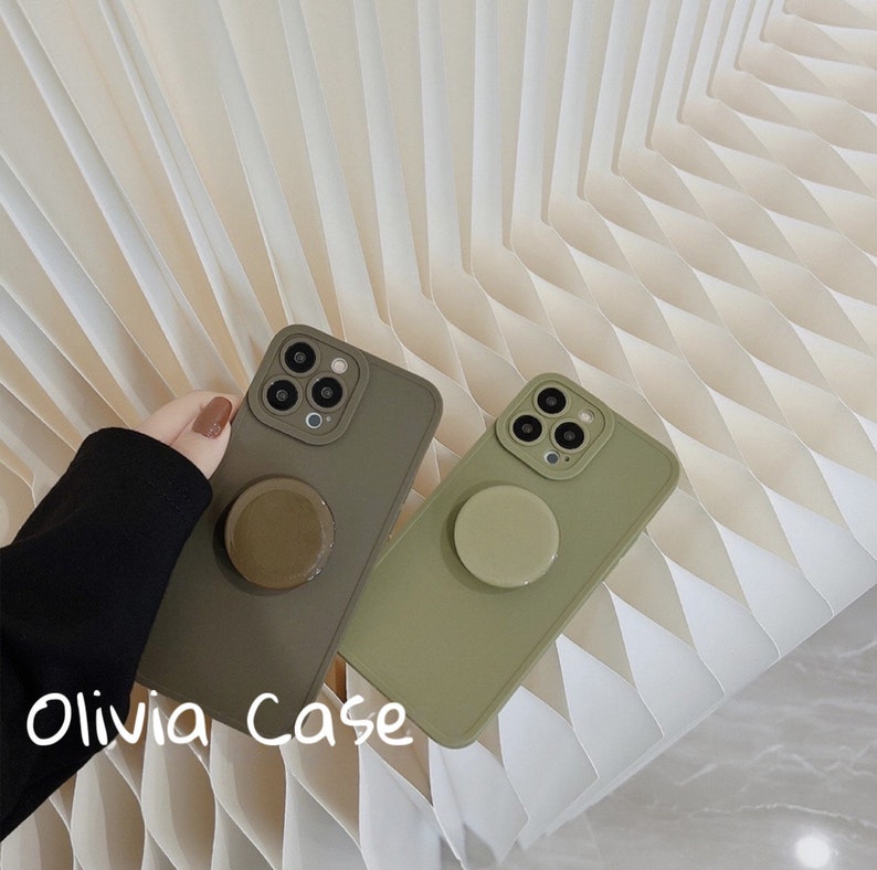 May include: Two green phone cases with a pop socket on the back. The cases are made of a soft, silicone material. The text "Olivia Case" is written on the bottom of the image.