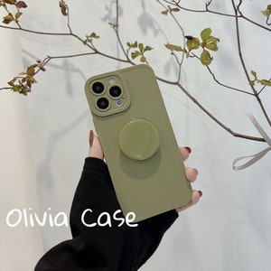 May include: A green phone case with a pop socket. The case has a camera lens cutout and the text "Olivia Case" is printed on the bottom.