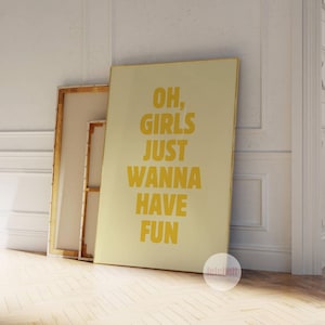 Puede incluir: Una impresión sobre lienzo beige con un marco dorado que presenta el texto "Oh, girls just wanna have fun" en letras amarillas.