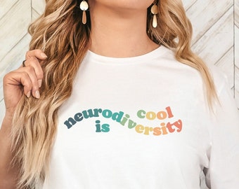 May include: White t-shirt with the text "neurodiversity is cool" in rainbow colors.