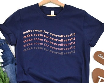 May include: Navy blue t-shirt with the text "make room for neurodiversity" repeated five times in a gradient of pink and red.