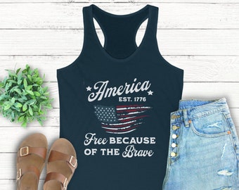 May include: A navy blue tank top with a distressed American flag graphic and the text "America Est. 1776 Free Because Of The Brave".