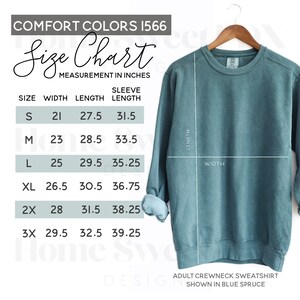 Puede incluir: Tabla de tallas para una sudadera con cuello redondo en azul abeto. La tabla muestra las medidas en pulgadas para el ancho, la longitud y la longitud de la manga para las tallas S, M, L, XL, 2X y 3X.