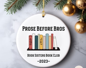 May include: White ceramic Christmas ornament with the text "Prose Before Bros Book Sisters Book Club -2023-" and a graphic of a bookshelf with colorful books.