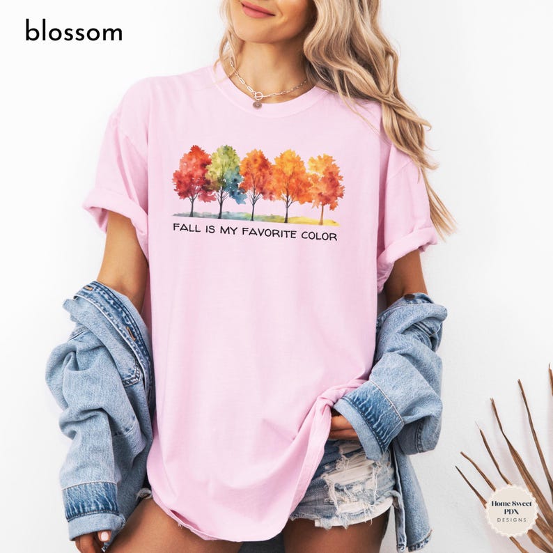 May include: A pink t-shirt with a watercolor design of five trees with fall foliage. The text "Fall is my favorite color" is printed below the trees.
