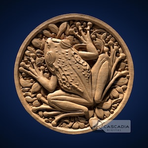 May include: A wooden carving of a frog sitting on a bed of leaves. The frog is carved in a realistic style and has a detailed texture. The carving is circular and has a smooth, polished finish.
